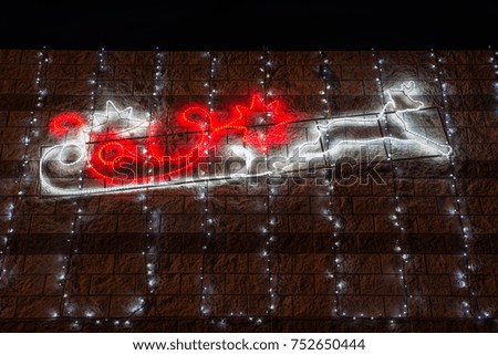 Profile of the sleigh and reindeer of Santa Claus with white and red christmas lights at night. Christmas background