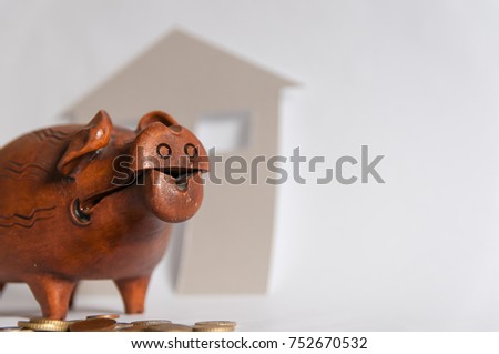 Piggy bank, coins, cardboard house on the background, conceptual life saving picture.