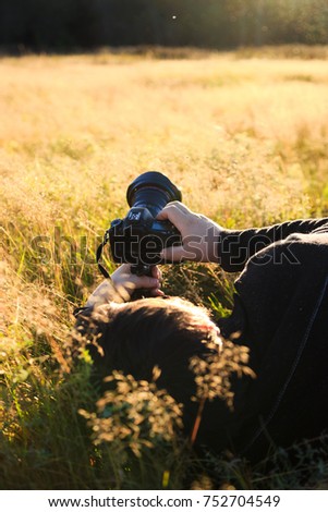 Nature photographer taking photo of wildlife. Man in the grass with a camera