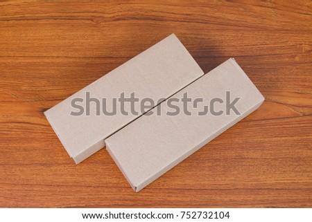 Empty Package brown cardboard box mock up for long items on bright wooden table with copy space.