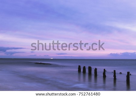 long exposure of a sea during sunrise with wooden poles