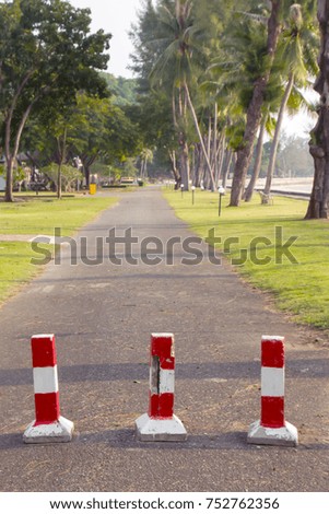 Red and white barriers are used to prevent vehicle passage.There is a rock that is blurred to the foreground.This image is design of blur.