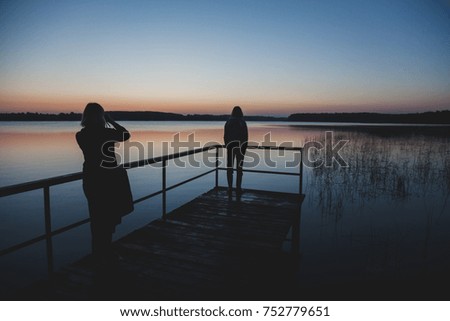 Two friends looking at sunrise by the lake
