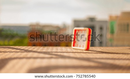 the clock in the warming sunshine on the morning and background of the cityscape from the high floor view