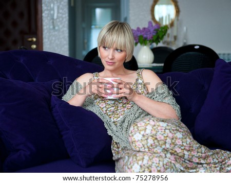 woman drinking coffee while sitting on the sofa at home living room