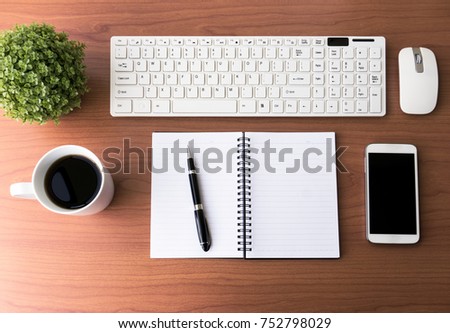 Top View Of Office Desk With Computer Keyboard, Smart Phone, Pen, Notepad, Mouse and Cup of Coffee on Wood Background. 