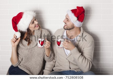Smiling couple in Santa hat and Christmas cup.