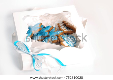 Ginger delicious gingerbread in the form of snowflakes and fir trees in a stylish gift box on a white background. Holiday gift