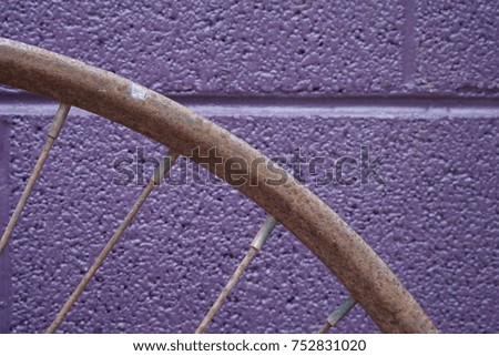 Rusty bike rim against purple wall.