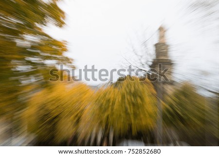 Blurred autumn picture with church steeple in background.