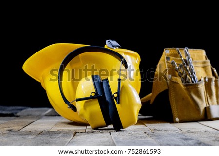 Protective clothing, helmet, gloves and glasses. Hearing protectors. Safety accessories on a wooden table. Black background.