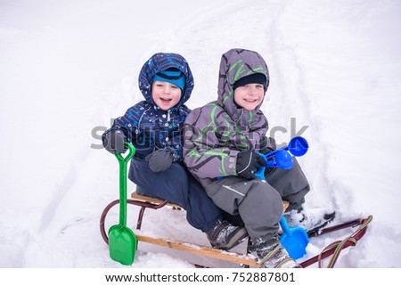 Winter holidays fun. Two boys have fun together sliding on a pleasant winter day.