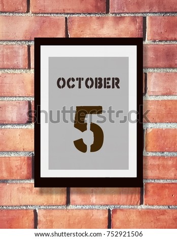 October 5th. 5 October calendar on the wood photo frame with brown brick background.