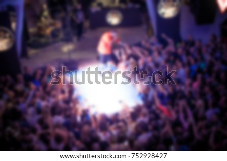 Blurred for background. Concert in night club. Rear view of crowd with arms outstretched at concert. cheering crowd at rap concert. Crowd at music concert, audience raising hands up