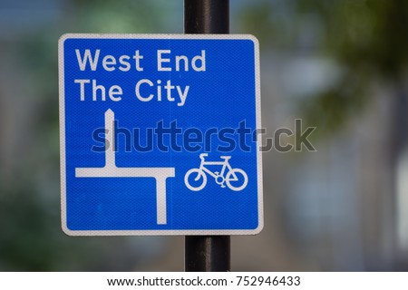 A street sign in London directs cyclists along a cycle route towards the West End and City districts