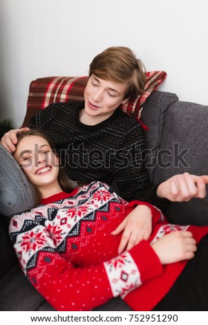 Portrait of beautiful couple lying on sofa at home and happily spending time together