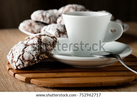 Delicious appetizing chocolate cookies cracked on a plate on a wooden table and a cup of coffee with space for text