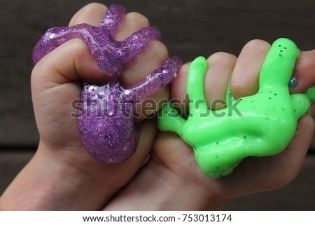 purple and green slime squeezed in kid's hands Royalty-Free Stock Photo #753013174