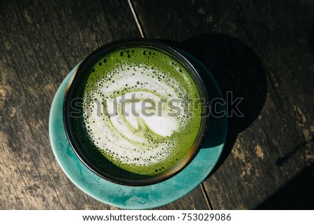 A cup of green tea latte pattern in a blue cup on wooden background