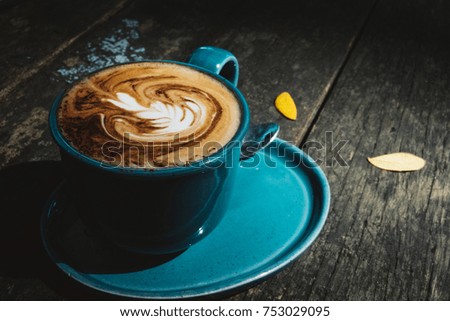 A cup of coffee with latte art pattern in a blue cup on wooden background