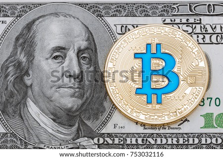 Golden cryptocurrency blue bitcoin on hundred dollar banknote background. High resolution photo.