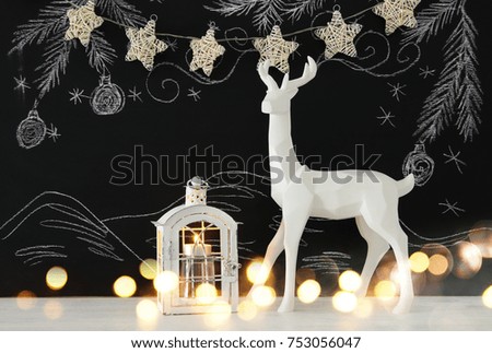 White reindeer on wooden table over chalkboard background whith hand drawn chalk illustrations.
