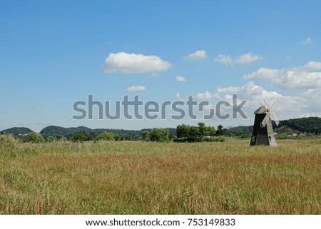 a windmill and an arbor in reed field, against blue autumn sky