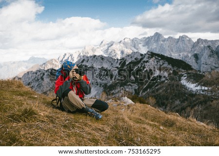 Mountain and nature photographer with his backpack and equipment on the mountain peak taking a photograph