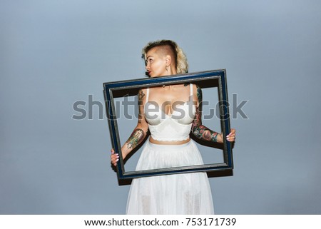 Freaky blond girl with picture frame bringing attention to breasts
