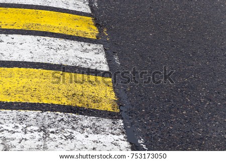 old worn road pedestrian crossing with white and yellow stripes, close-up photo