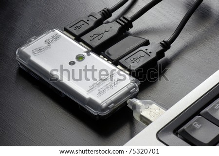 Full USB hub plugged into a laptop resting on dark wood grain office desk
