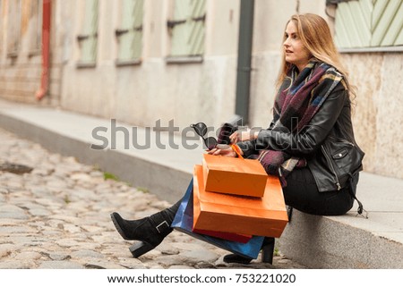 Beautiful blond girl sits on a street with shopping bags