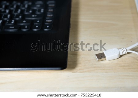 Whit USB  cable with laptop on wood desk