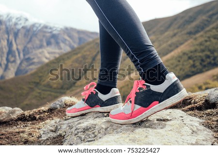 walking women's legs in sneakers against the background of the mountains