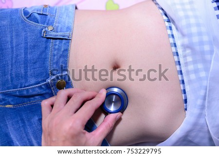 Bowel sounds assessment /  Stethoscope / Abdominal assessment. The doctor uses a stethoscope on abdomen of women for physical examination / pregnancy.