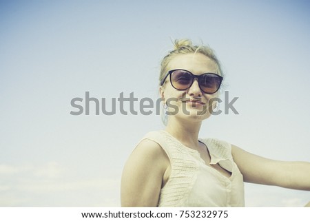 Portrait of a cute teenager young woman stand against blue sky background. wearing sunglasses. filtered image to vintage tone. light effect added.
