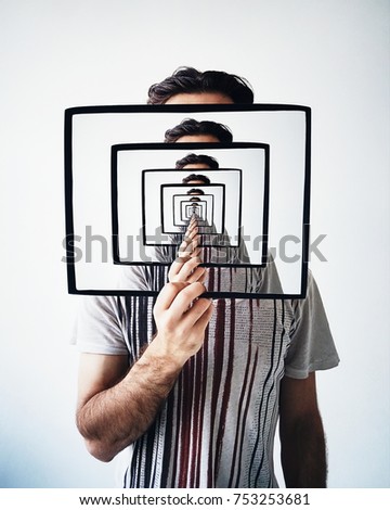 Creative recursion concept. Young man holding frame with recursion effect Royalty-Free Stock Photo #753253681