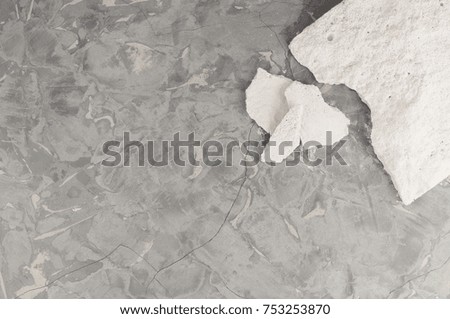 One broken white stone and fragments on background of dirty gray concrete