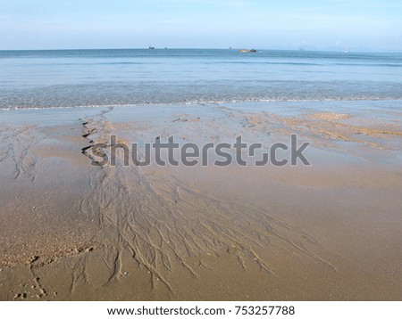 Coast after large ebb on the sea. Sandy patterns of flowing water. Tropical climate. Islands and ships on horizon.