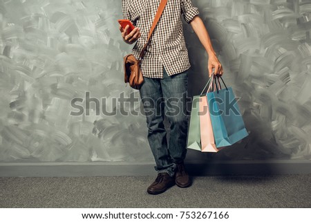 Young asian man holding color paper shopping bag in the living room.