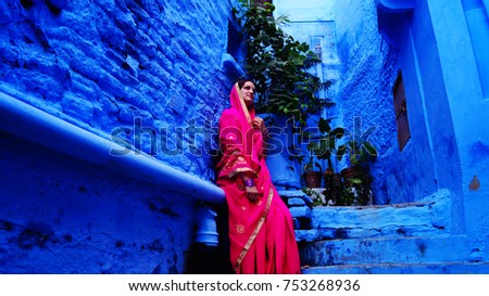 Young and beautiful woman in indian sari (saree) on the streets of Jodhpur, Rajasthan, India. Woman posing on the steps in traditional indian clothes.