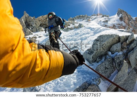 Tied climbers climbing mountain with snow field tied with a rope with ice axes and helmets first person. Royalty-Free Stock Photo #753277657