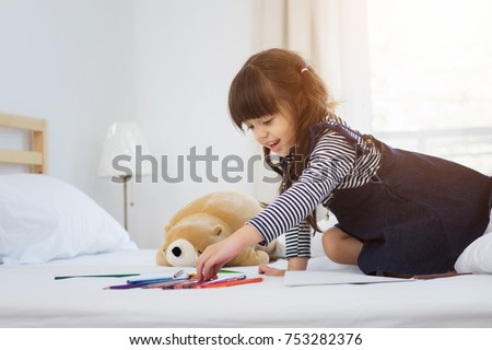 Child draws with color pencils on a large sheet of paper at home