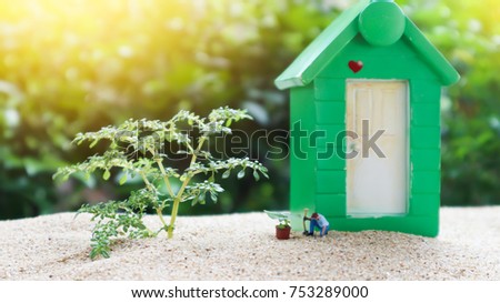 Miniature Greenhouse concept, alone of miniature mini figures with planting tree in front of the green house. protect nature and environment concept