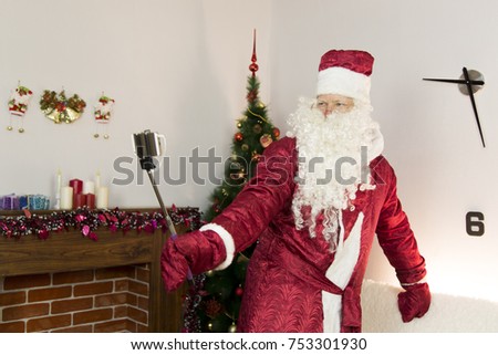 Santa Claus takes pictures of himself.
In the room near the Christmas tree, Santa Claus is holding a self-stick and taking pictures of himself in different ways.