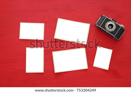 Top view image of old camera and empty photo frames on red wooden background. Flat lay. For photography and scrapbook montage