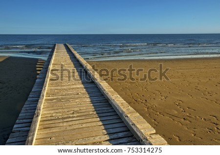 Beach landscape with pier and waves of the sea in the sand (Jesolo, Italy)