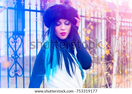 American girl with colored fashionable blue locks in her hair. Stylish winter Casual style. A beautiful young woman in a hat, magical moments of winter. Photo with colored lights