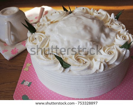 White cake . Cake with a rose-like cream, placed on a pink pad, placed on a wooden floor. Backdrop in natural light