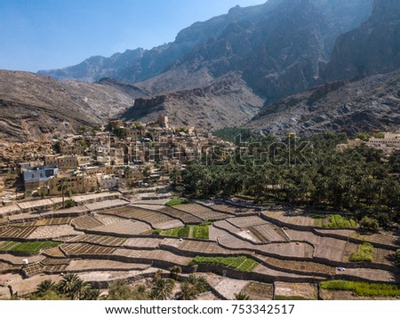 Aerial drone view of an old traditional Omani mud village in the mountains among date palm trees. Balad Seet, Oman.